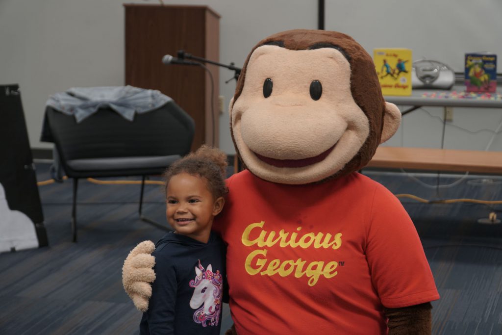 Curious George taking a photo with a toddler